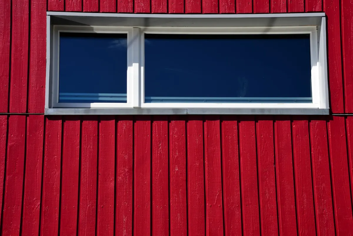 Red painted vertical board and batten wall with a wide modern white-framed window