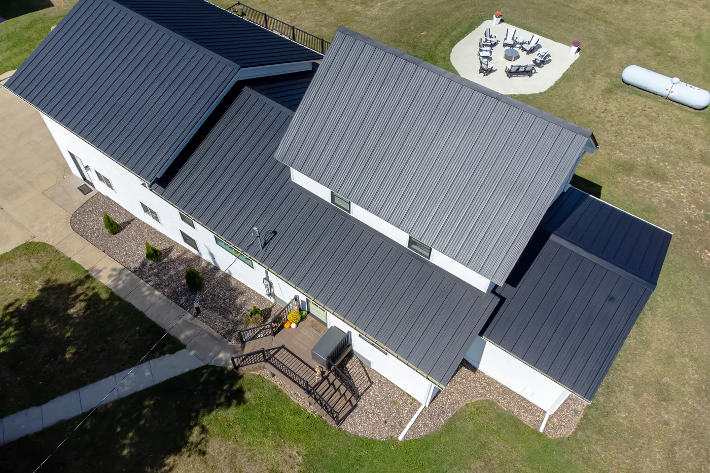 Aerial view of a white two-story house with a dark gray standing-seam metal roof