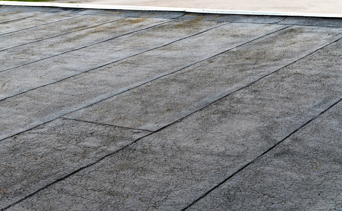 Weathered modified bitumen flat roof with a cracked, alligatored surface and visible lap seams