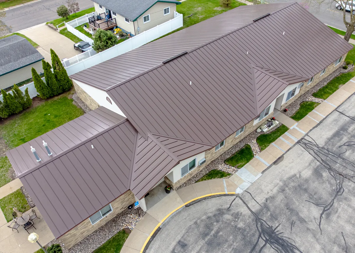 Standing seam metal roof panels on a house, seen from above, with raised vertical seams running from ridge to eave